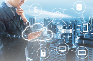 Double exposure of businessman connected Cloud technology with internet and wireless network with his smart phone and city of business background in business trading concept