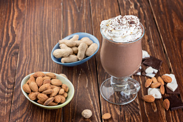 Homemade milkshake ( smoothie) with nuts and chocolate pieces on rustic wooden table