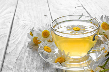 cup of tea with chamomile flowers on rustic wooden background