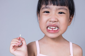 Asian Chinese little girl holding her missing tooth