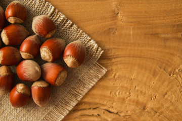 Hazelnuts in a shell on a napkin from sackcloth on a wooden background.