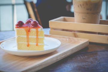 Sponge cake with cherry syrup. Peace of cherry cake serve with iced coffee in cozy outdoor cafe.