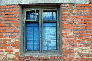 Fototapeta na wymiar старое окно с форточкой заколоченное досками и решёткой на кирпичной стене