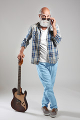 Senior man with guitar on grey wall background