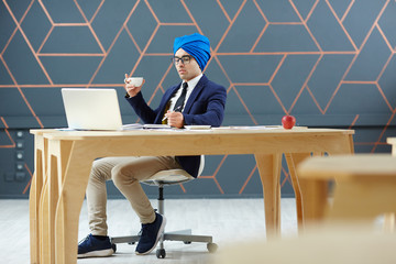 Businessman in turban and formalwear working in office or tv studio