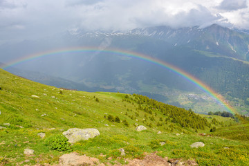 A rainbow coming through the rainy clouds in the mountains