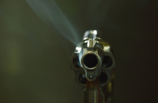 revolver gun muzzle with smoke floating in the air after shoot on black background