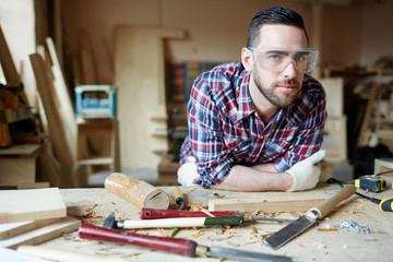 Carpenter in protective eyeglasses in his workshop