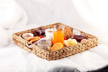 breakfast in bed with fruits and pastries on a tray -waffles, croissants, coffe and juice