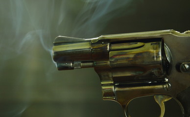 revolver gun with smoke floating in the air after shoot on black background