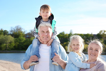 Fototapeta premium Happy grandparents with little children on river bank