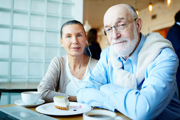 Affectionate couple listening to music in cafe