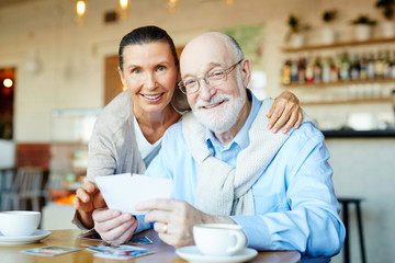 Obraz na płótnie Canvas Senior couple looking through photos in cafe