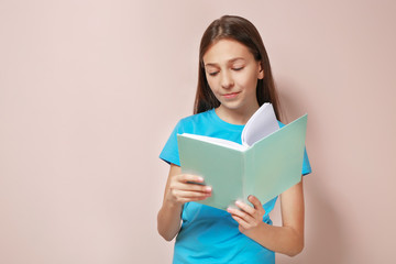Cute pretty girl with book on color background