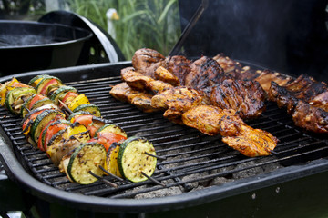 Spieße aus Gemüse und Fleisch werden gegrillt auf einem Kugelgrill