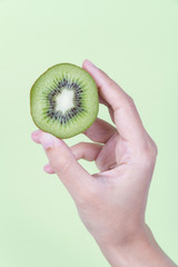 Holding kiwi fruit on green background