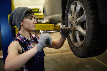 Woman with hand-tool repairing or changing wheel