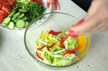 Female hands are cooking vegetable salad at the kitchen