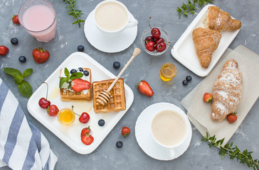 Breakfast concept flat lay with fresh berries waffeles, croissant and coffee. Top view