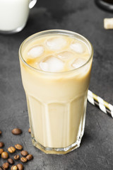 Ice coffee with milk in a tall glass on a dark background