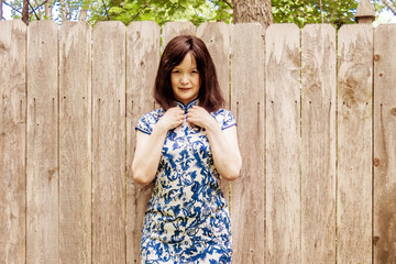Fototapeta premium A portrait of an Asian woman standing in front of a wood fence