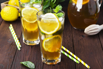 Ice tea with lemon and mint on a wooden background