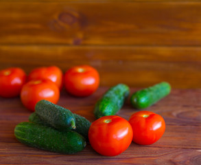 Summer vegetables on a wooden background. Cucumbers, tomatoes on the table