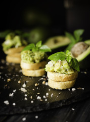 Toasts with pasta from avakado or guacamole and spices on wooden table with fruits, selective focus, concept