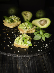 Toasts with pasta from avakado or guacamole and spices on wooden table with fruits, selective focus, concept