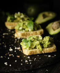 Toasts with pasta from avakado or guacamole and spices on wooden table with fruits, selective focus, concept