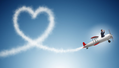 Man flying airplane and making heart shape