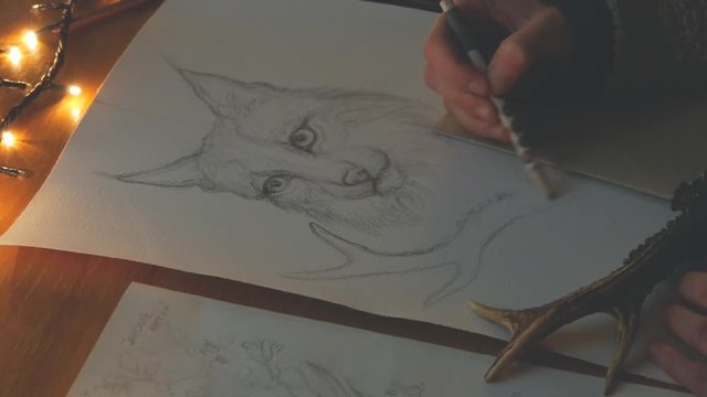 female artist painting a picture of a lynx with a brush on piece of paper