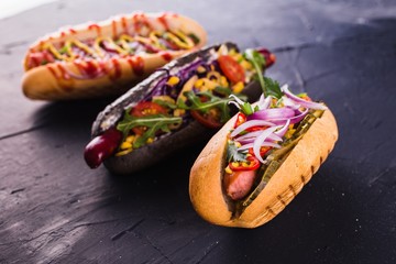 three hot dog on a dark background (close)