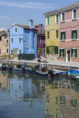 Fototapeta na wymiar BURANO - ITALY, APRIL 18, 2009: Panoramic view of colorful buildings and boats in front of a canal at Burano, a gracious little town full of canals, near Venice.
