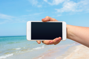 Beautiful woman's hand using smart phone at beach