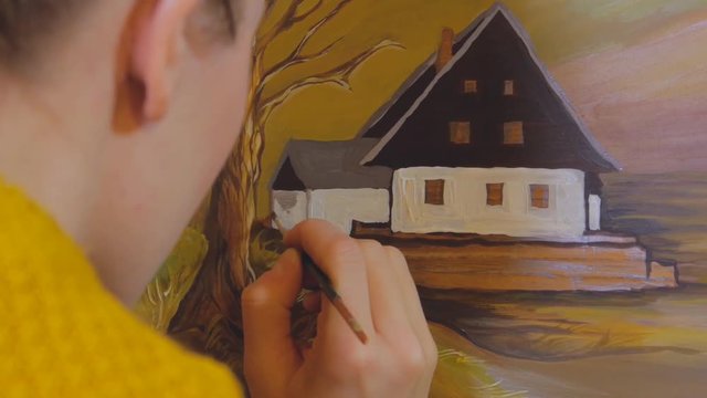female artist painting a landscape picture on a reclaimed wooden board