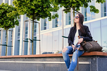 Brunette female student using tablet PC on a city street.