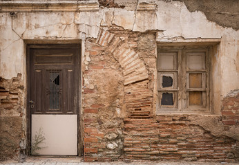 ancient wooden door and a window on a wall made of bricks