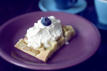 rhubarb cake with cream and blueberry on top