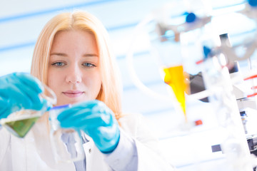 Female laboratory assistant with chemical experiment in scientific laboratory