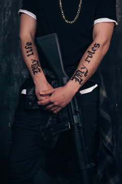 Unrecognizable criminal with sniper rifle closeup studio shoot. Armed white gangster man with weapon on dark background. Outlaw, ghetto, murderer, robbery concept