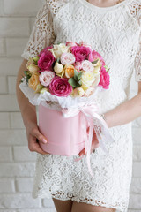 Unrecognizable girl with gift. Luxury rose bouquet. Colorful flowers boxing in pink box in the shape of a cylinder. Beautiful and sensual present for March 8, Valentine's Day