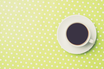 Overhead shot of of coffee cup on green dotted background