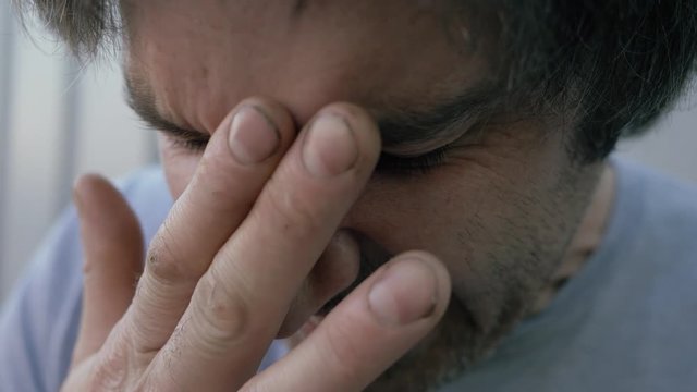 A man pinching his nose while experiencing pain.