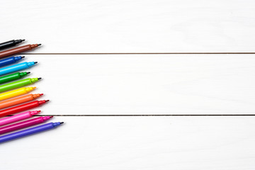 Close up shot of colorful markers on white wooden table