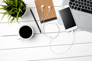White smart phone, laptop and accessories on white wooden table. Top view