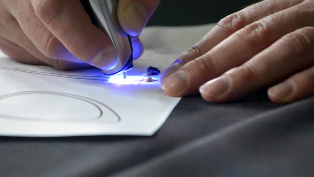 Drawing 3d pen draws with hardening photopolymer close-up. Person drawing with 3D pen that draws a liquid photopolymer that hardens under the action of the ultraphylet