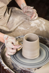 pottery, workshop, ceramics art concept - man works with potter's wheel and raw fireclay, yong male sculpt new utensils with hands, tool, fingers and water, top view, vertical