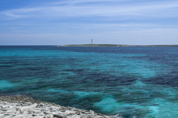 Aguas turquesas con la Isla del Aire y su faro en Menorca
