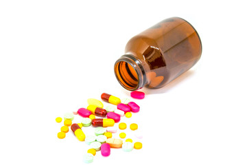 Many drugs overflow from the bottle on a white background.